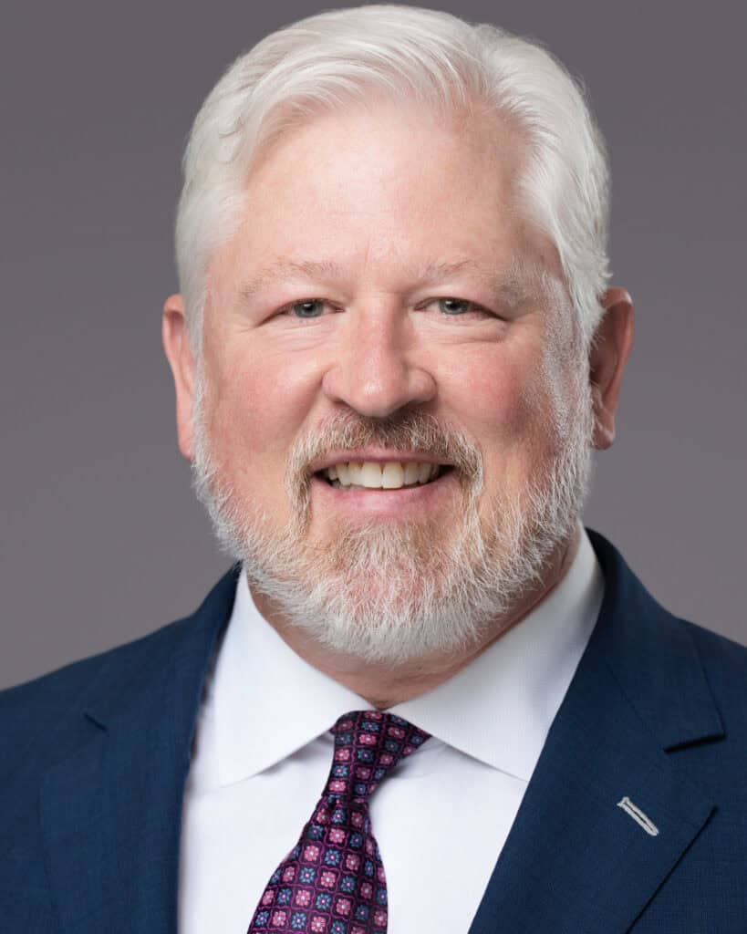 Smiling attorney in a navy suit and tie, Tampa lawyer headshot